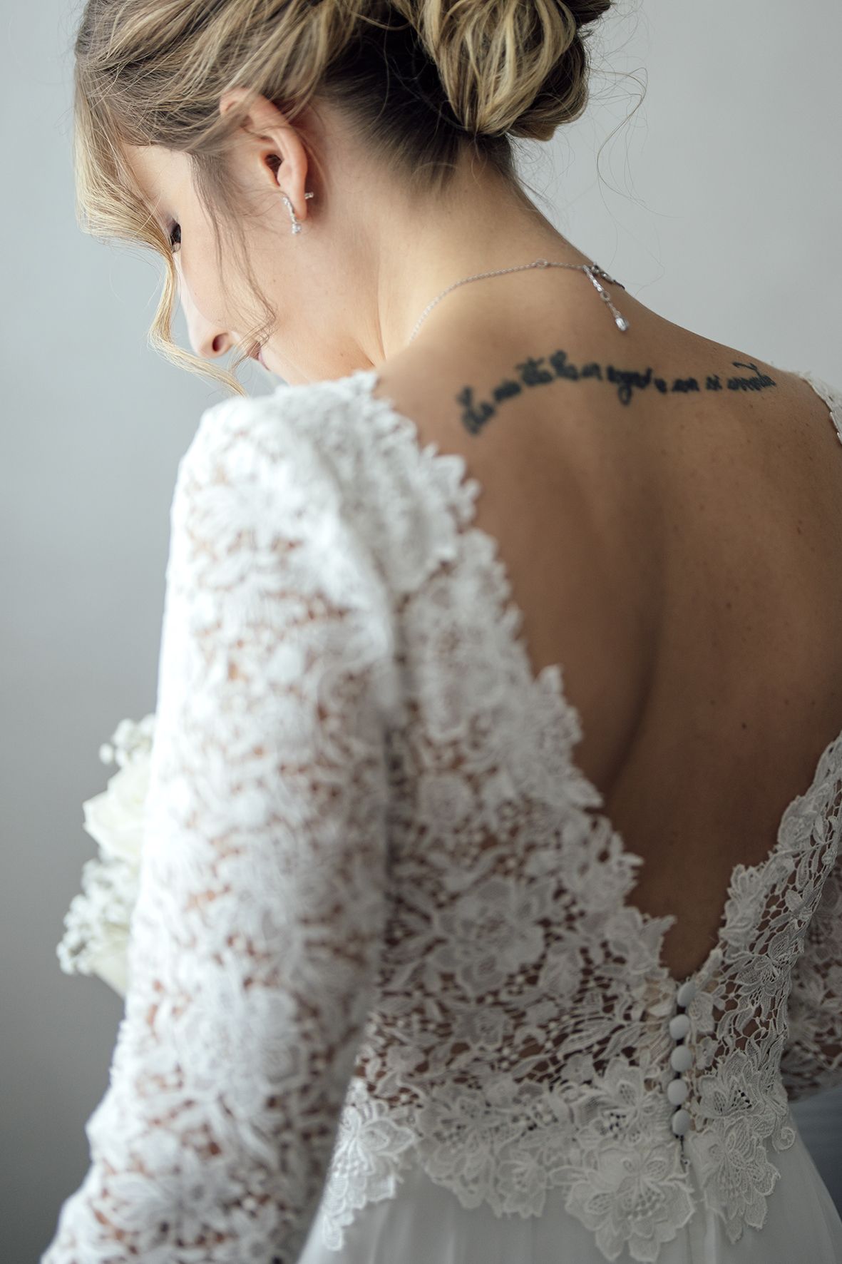 Detailed back view of delicate white lace wedding dress with intricate floral patterns.