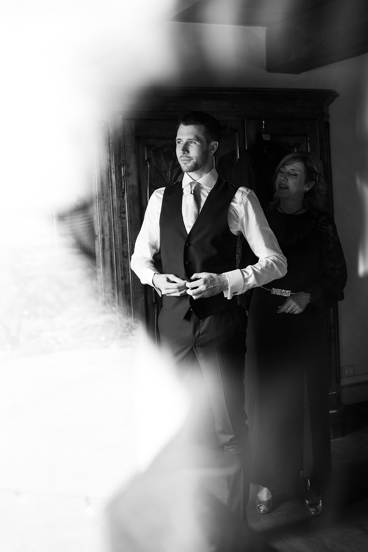 Black and white photo of formal attire preparation in dimly lit room.