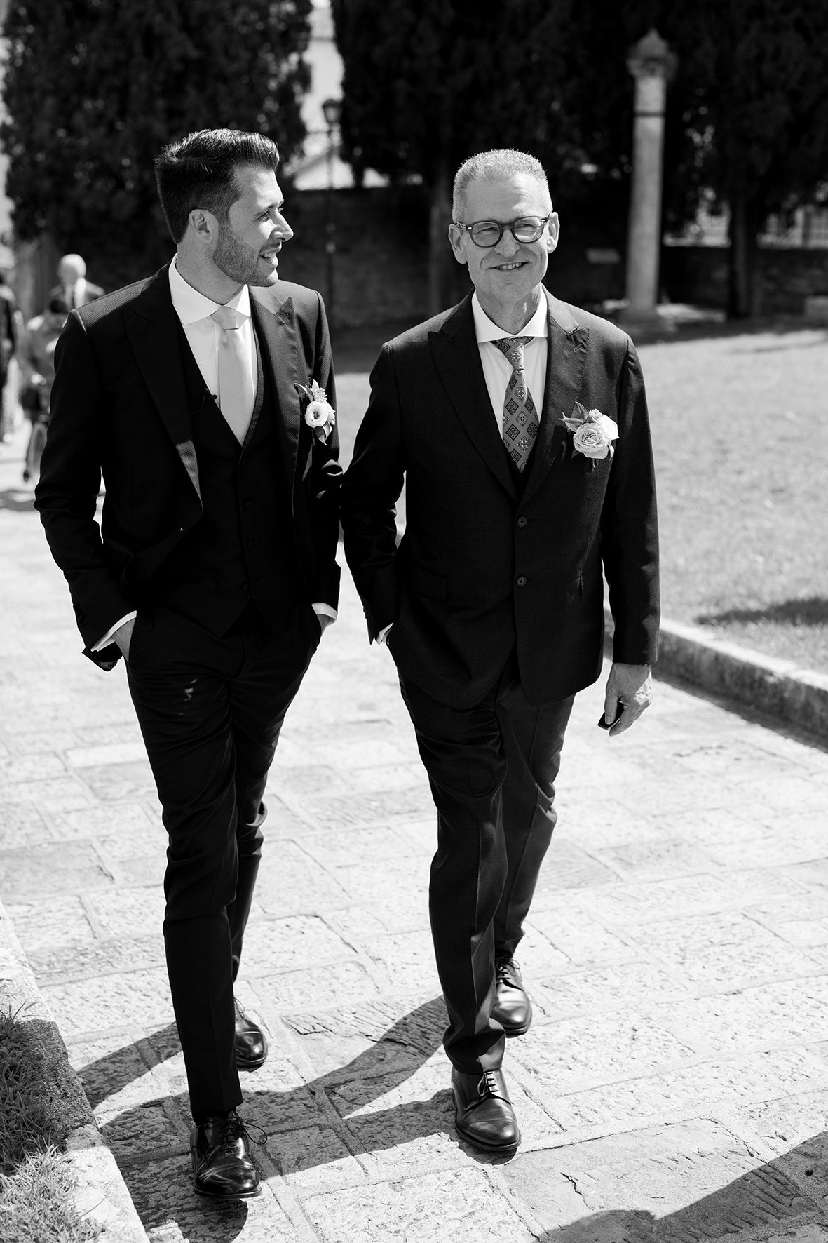 Black and white photo of groomsmen walking together on stone pathway.