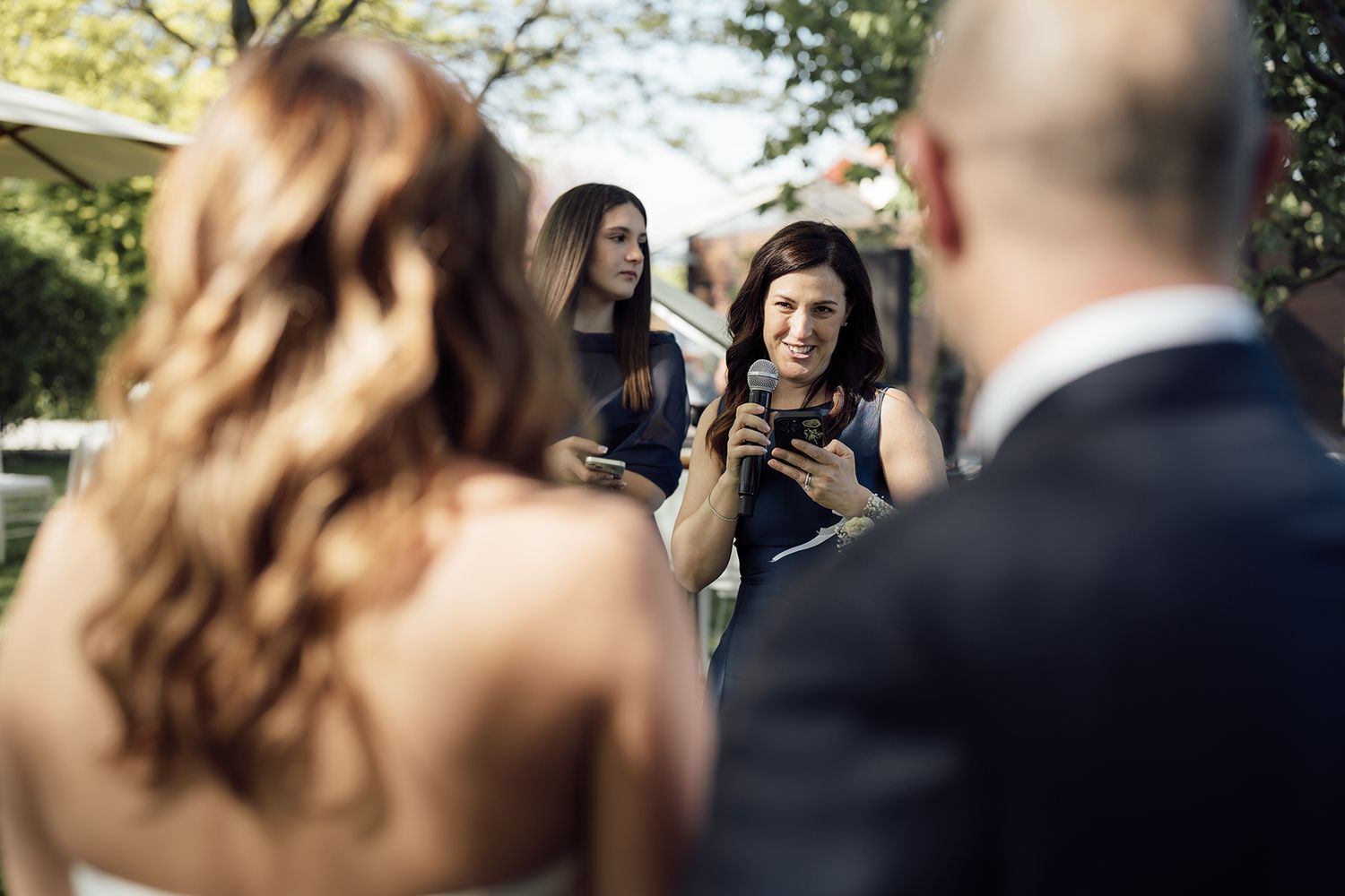 Candid moments captured during an outdoor wedding ceremony under trees.