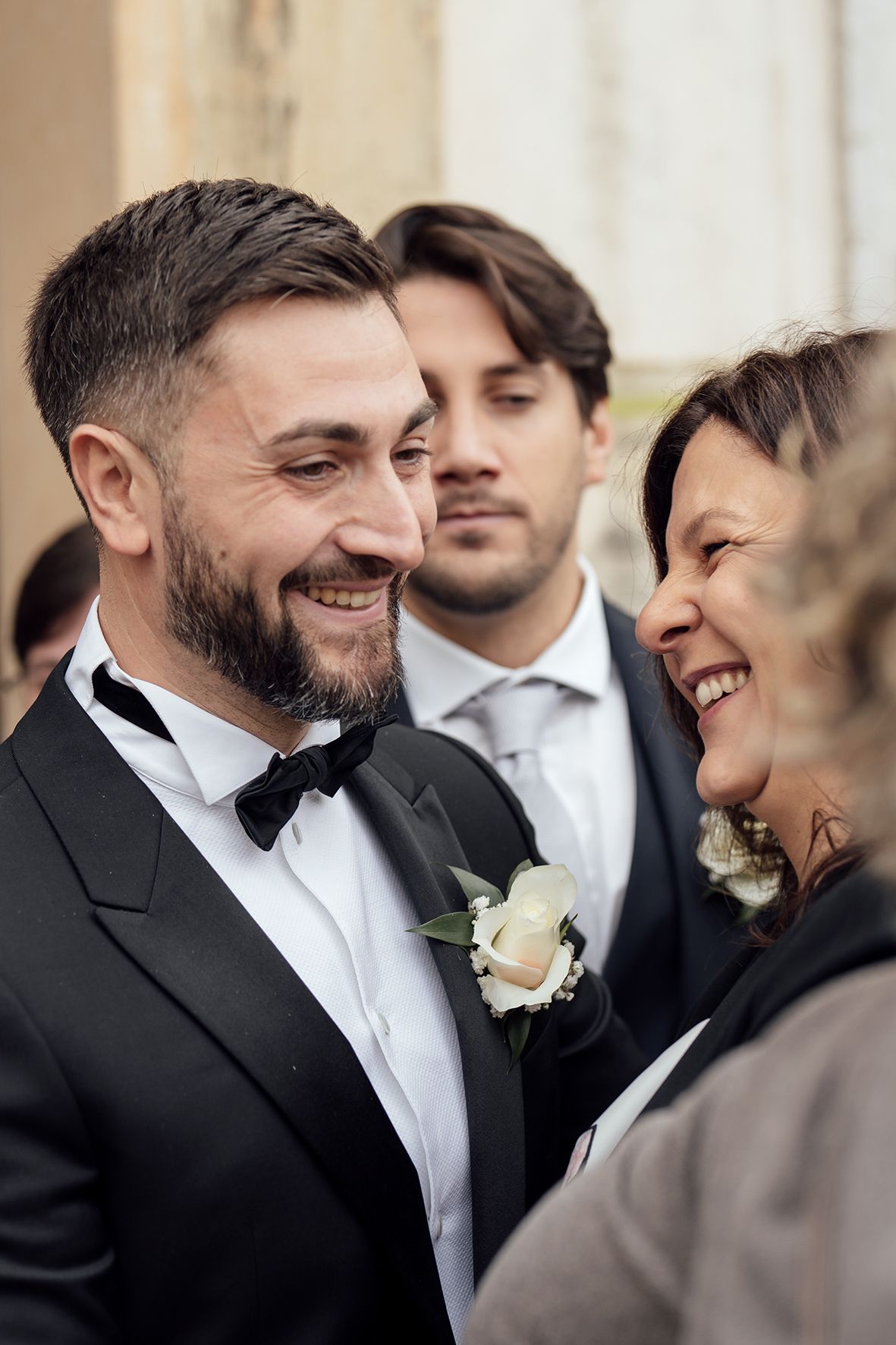 Candid moment of joyful laughter shared during wedding celebrations outside a historic building.