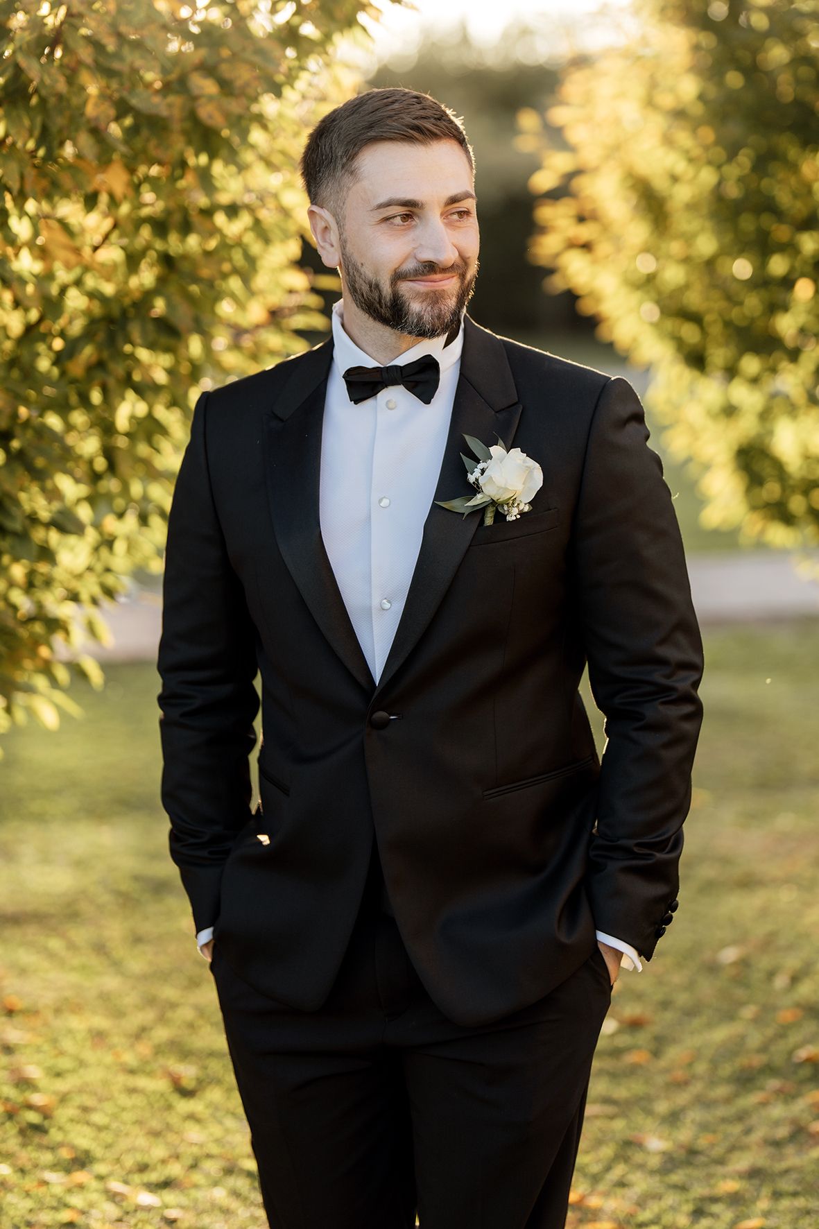 Classic black tuxedo with bow tie and boutonniere in autumn garden setting.