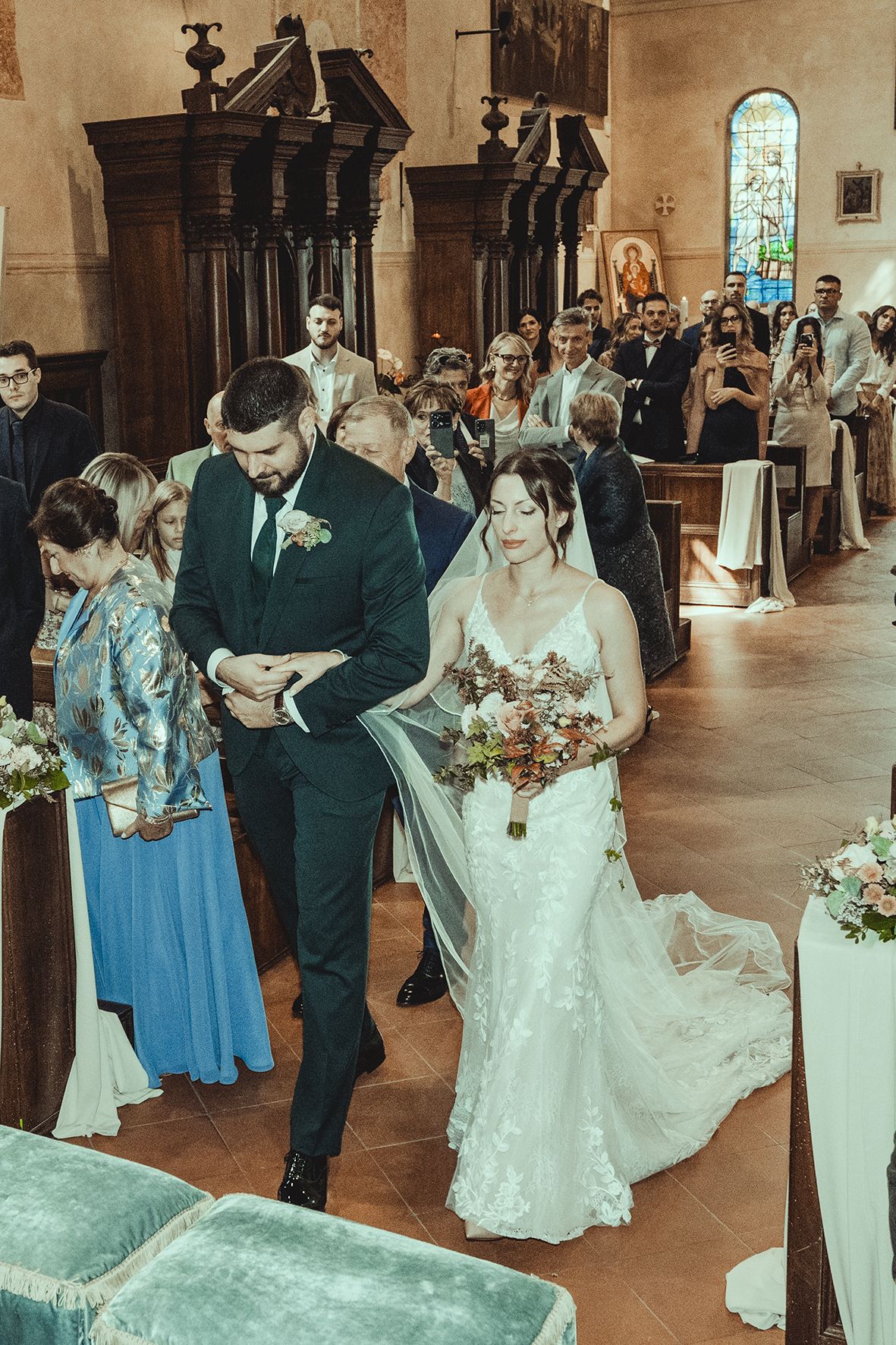 Wedding ceremony in progress inside historic church with wooden architectural details.