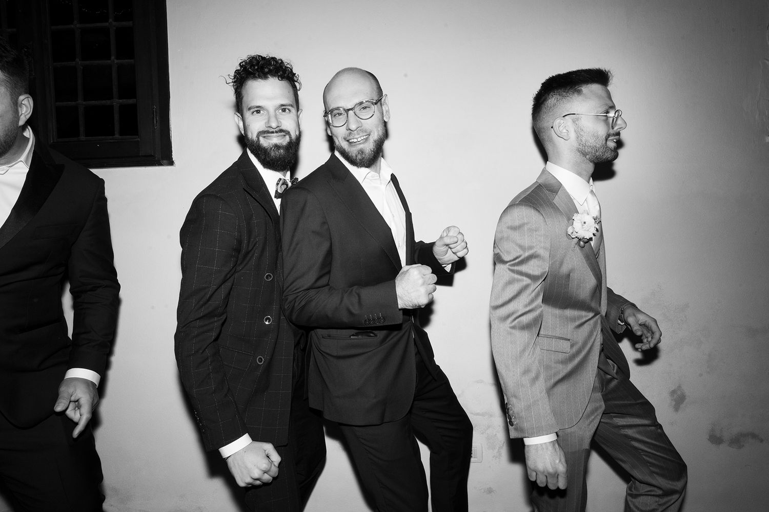 Black and white photo of wedding guests posing and laughing together at a celebration.