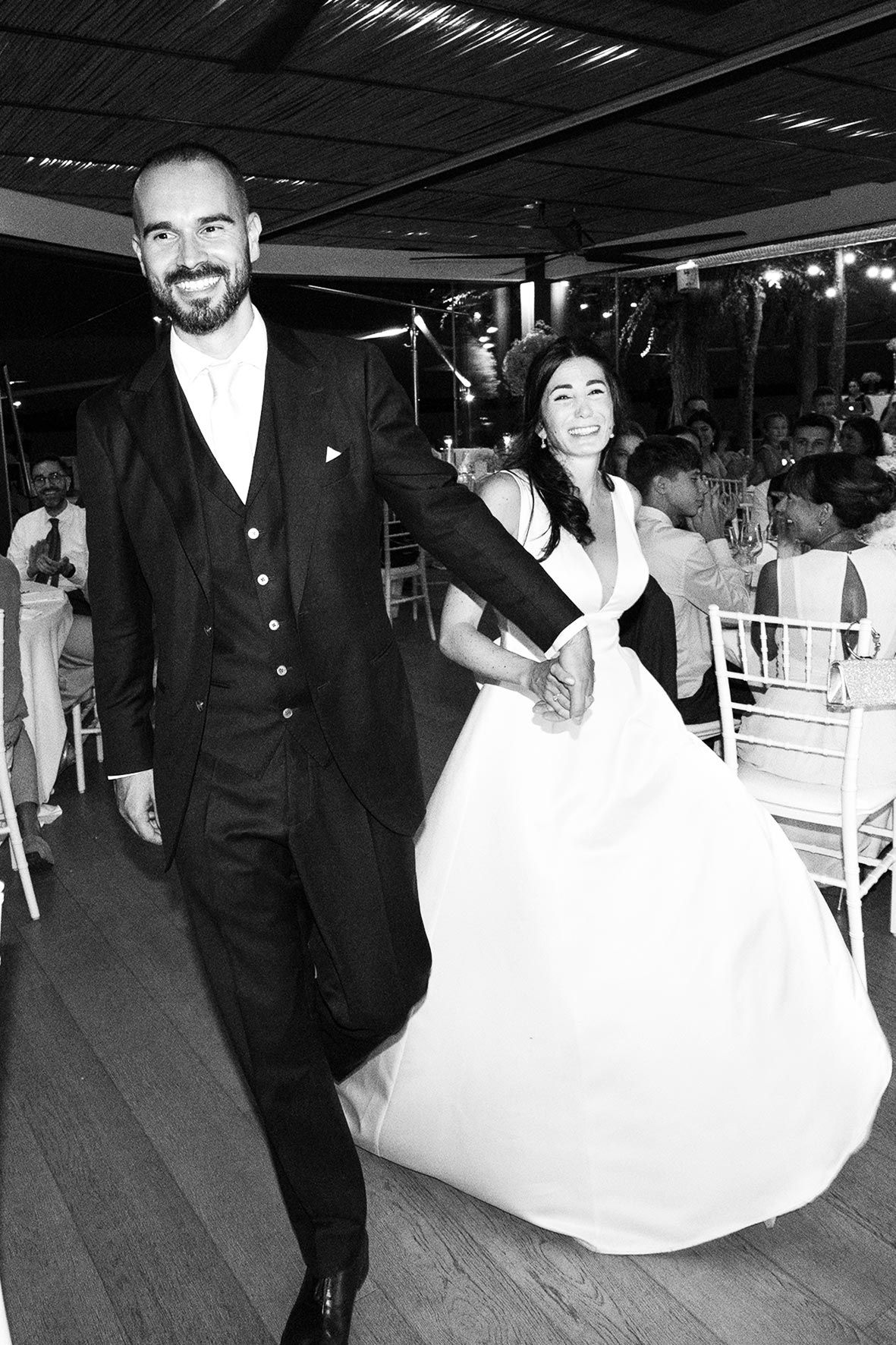 Wedding couple dancing on wooden floor with elegant black and white attire.