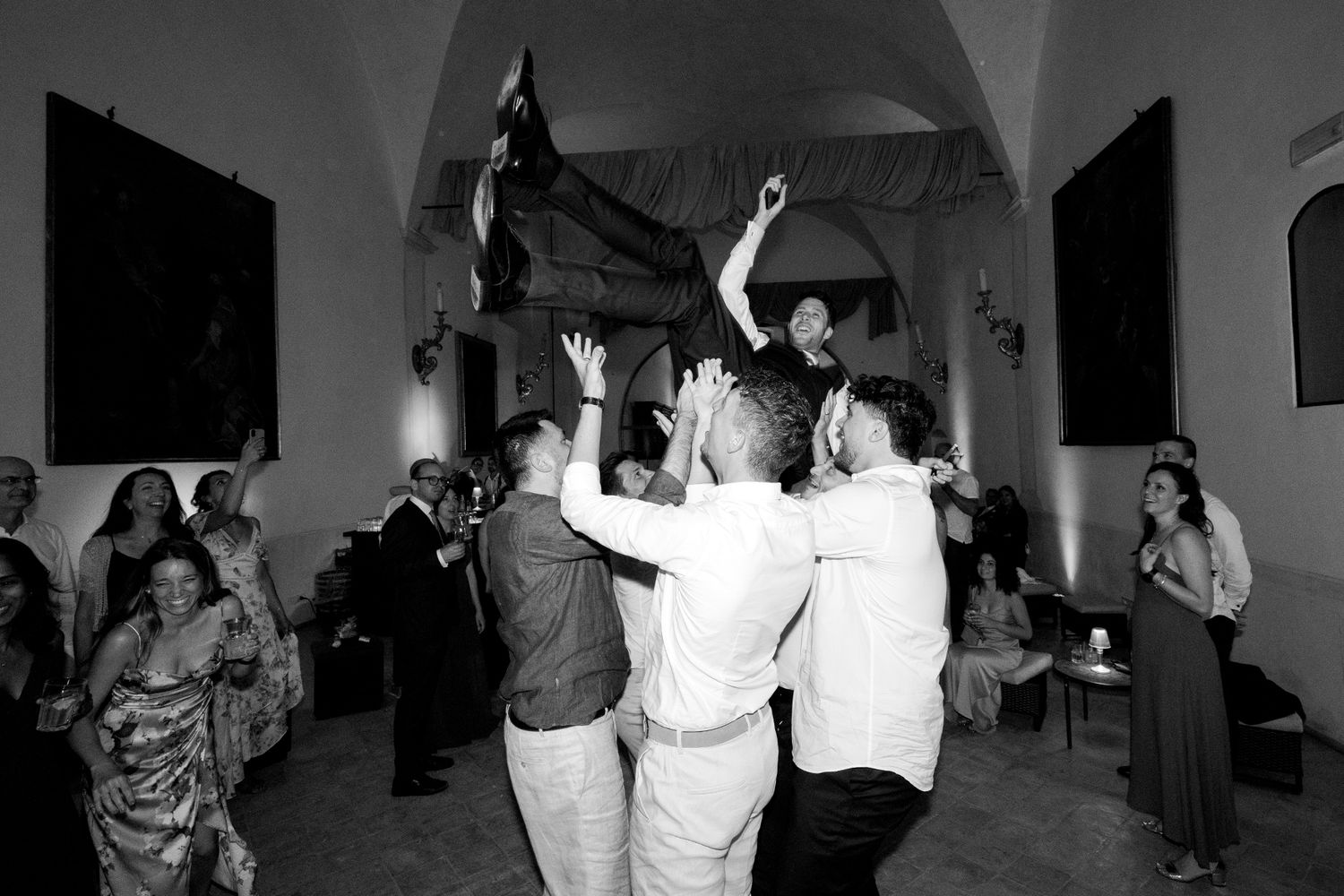 People dancing and celebrating at a wedding reception in black and white photography.