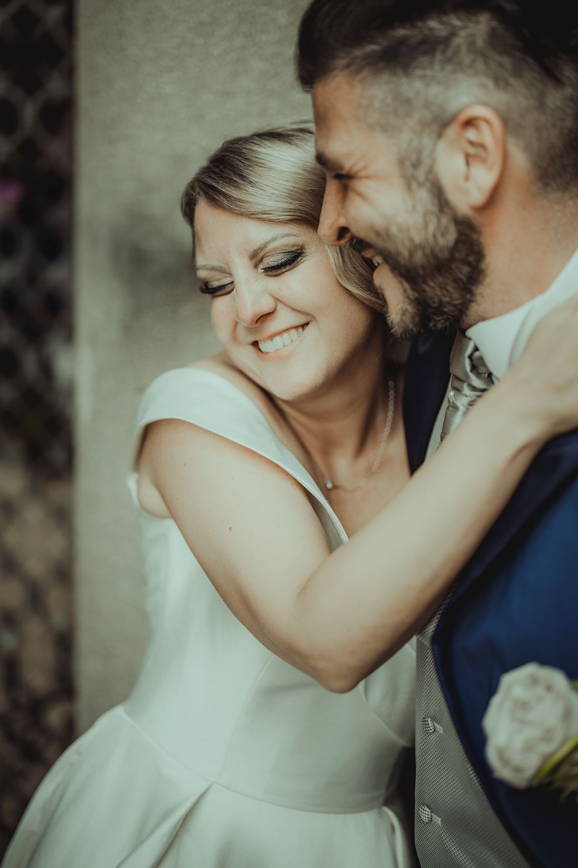 Close-up wedding portraits showing tender moments between bride in white and groom in blue.