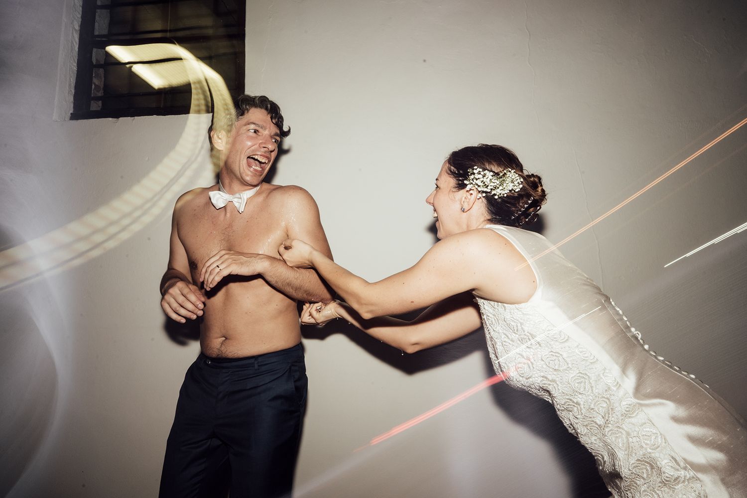 Candid wedding photo showing playful moment between newlyweds dancing.