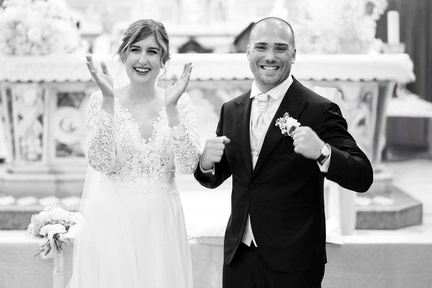 Black and white wedding photo shows couple sharing genuine laughter during ceremony.