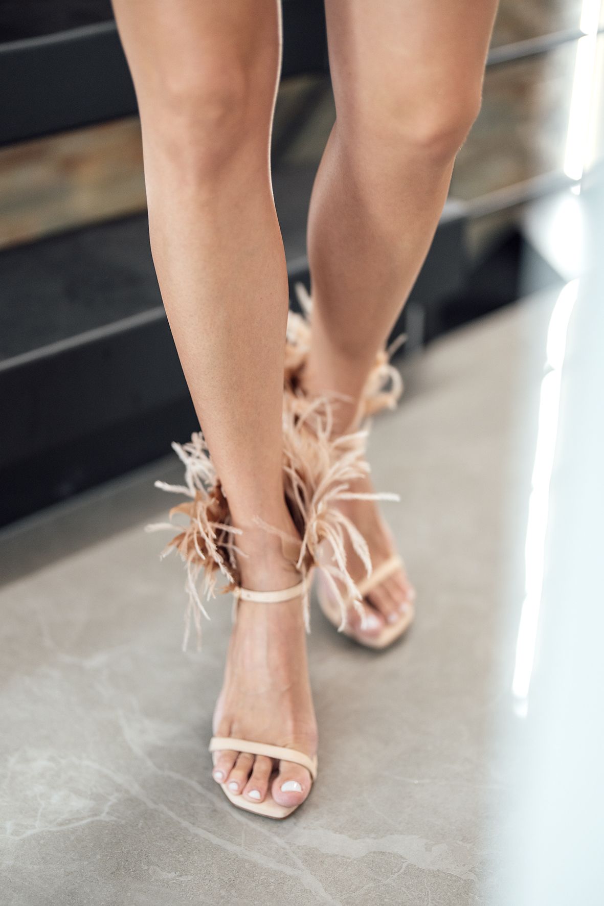 Detail shots of blush pink feathered bridal sandals on a concrete floor.