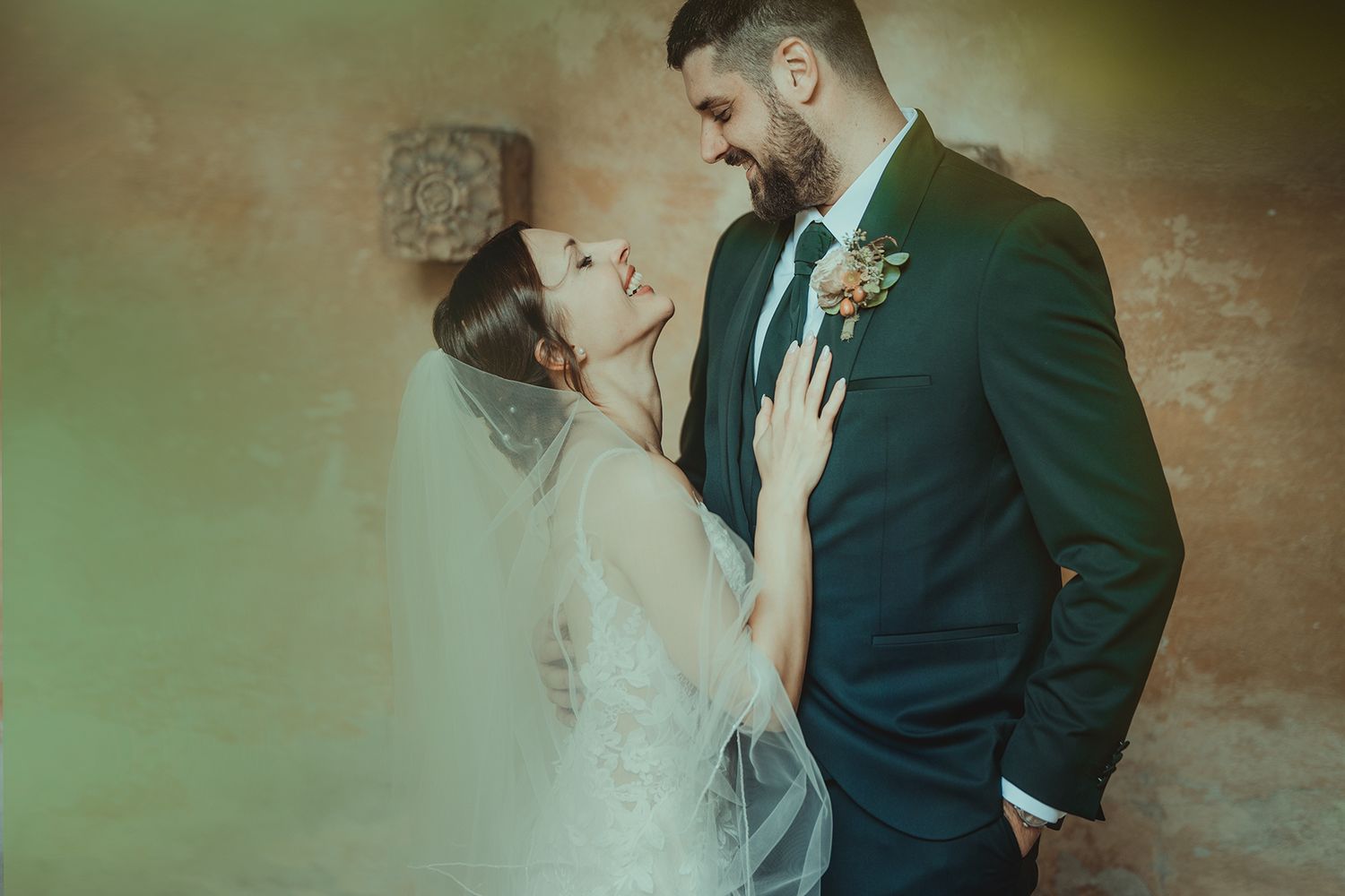 Intimate wedding moment captured against a rustic textured wall background.