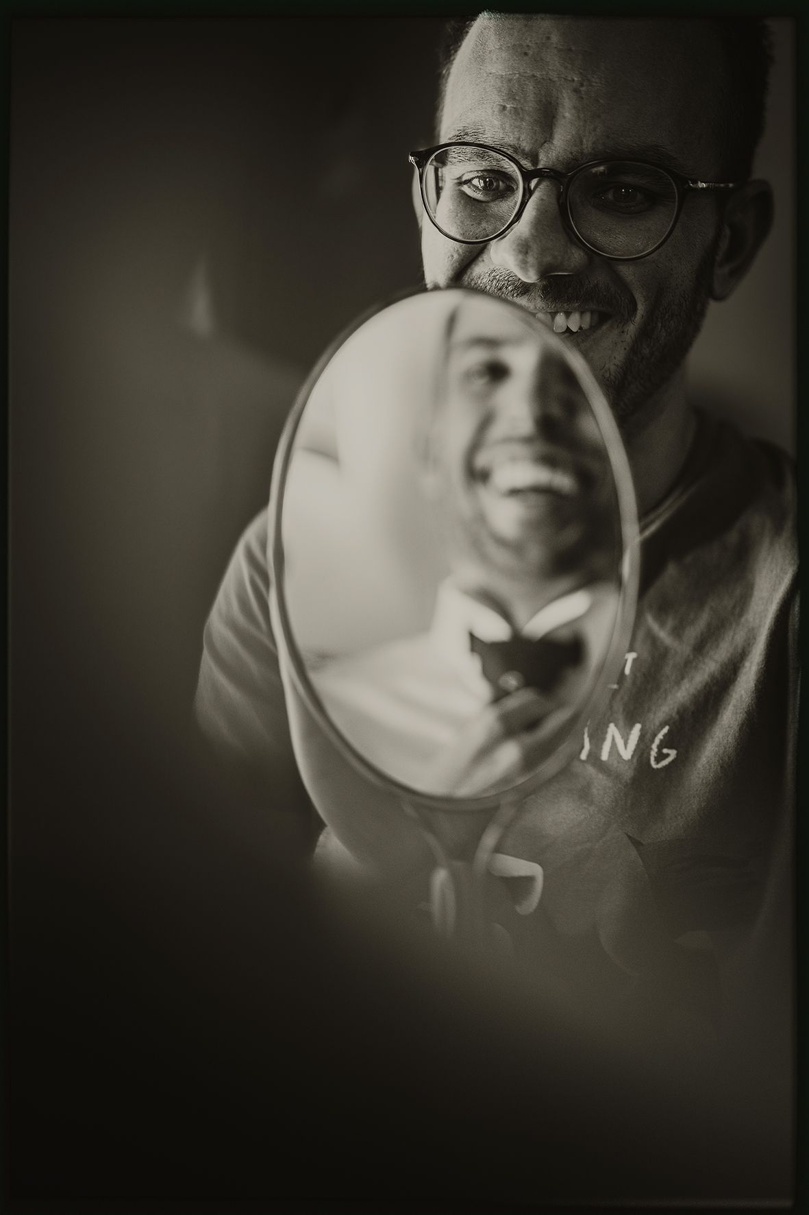 A series of moody black and white close-up portraits showing someone wearing glasses in dramatic lighting.