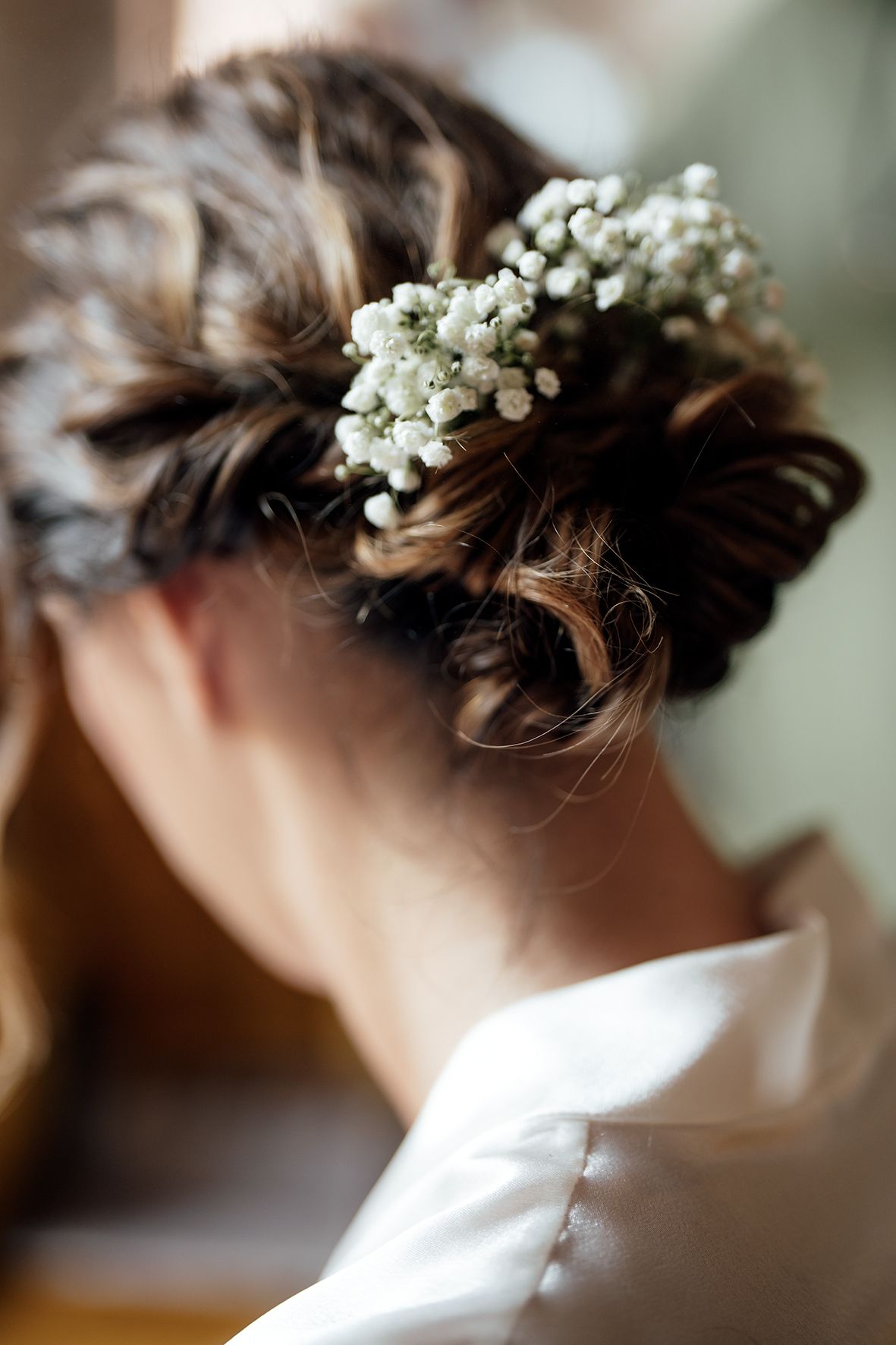 Delicate white baby's breath flowers adorn an elegant updo hairstyle.