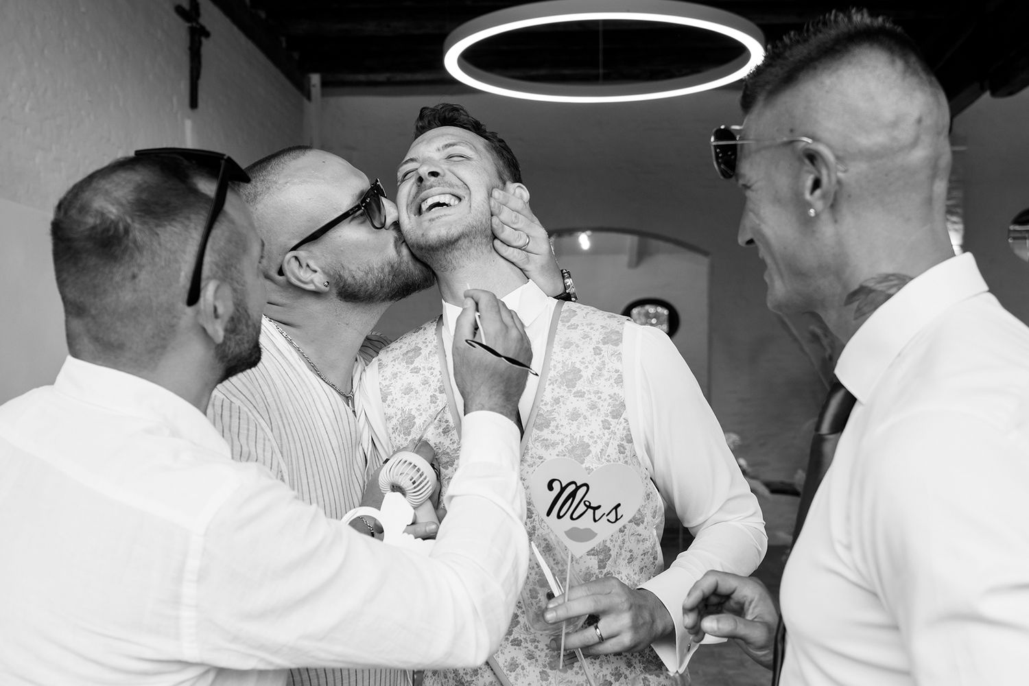 Candid black and white photo capturing laughter and celebration at wedding reception.