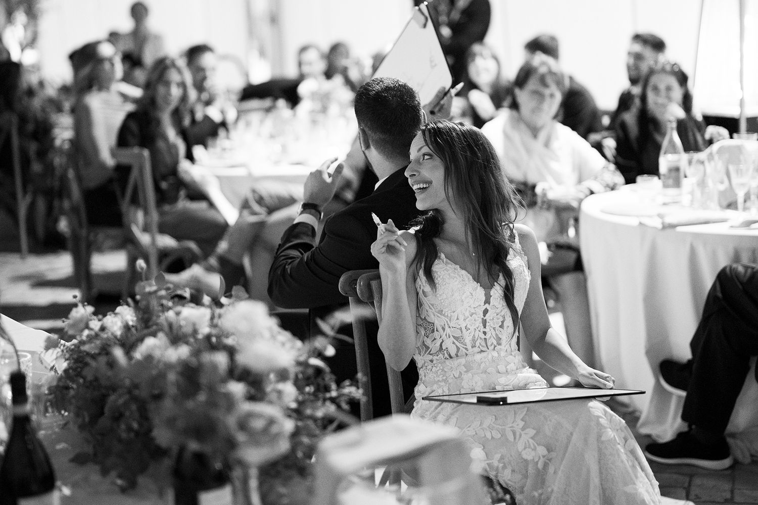 Wedding reception candid moments captured in black and white with guests at decorated tables.