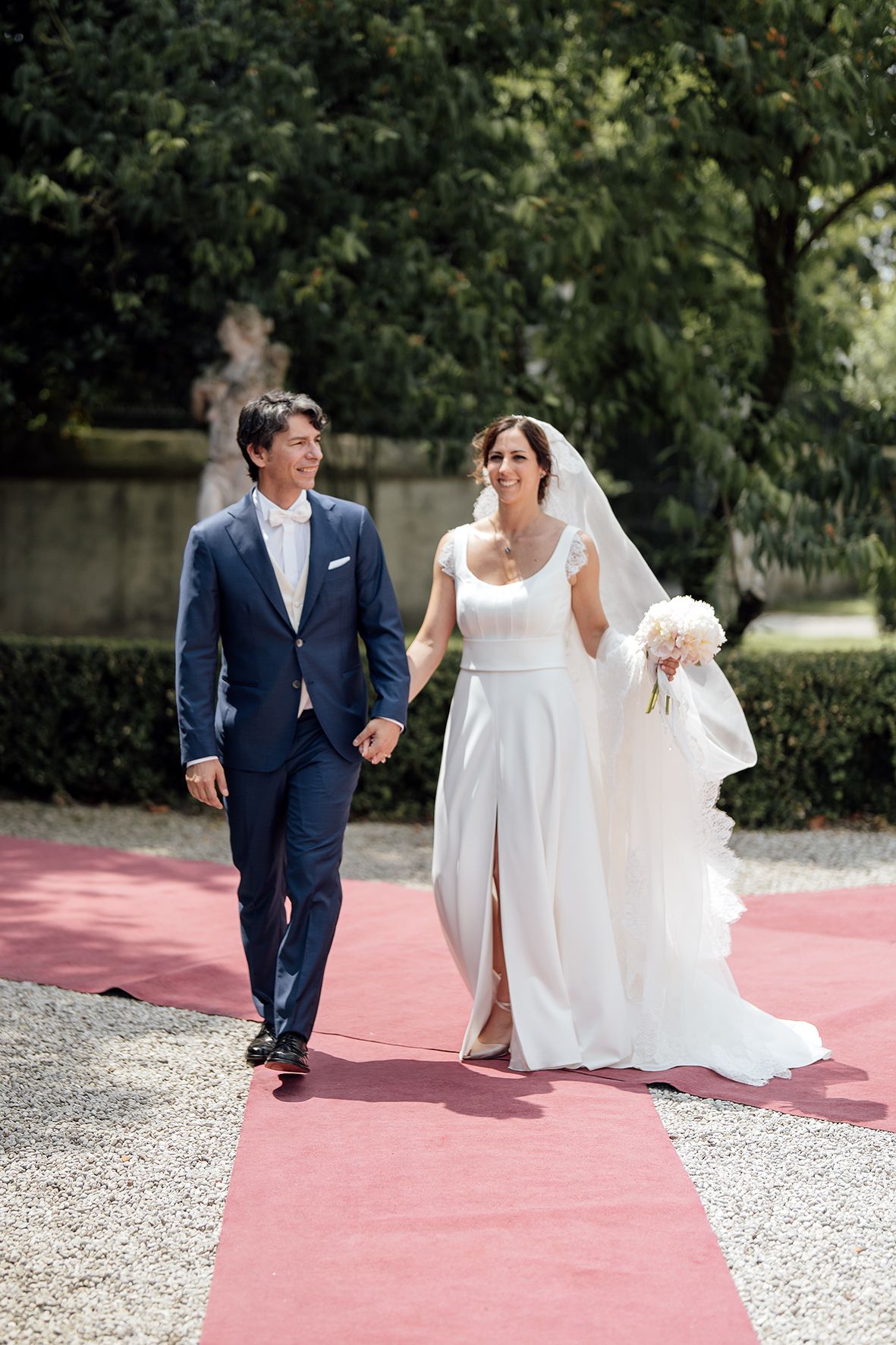 Couple walking along pink pathway during outdoor wedding photo session.