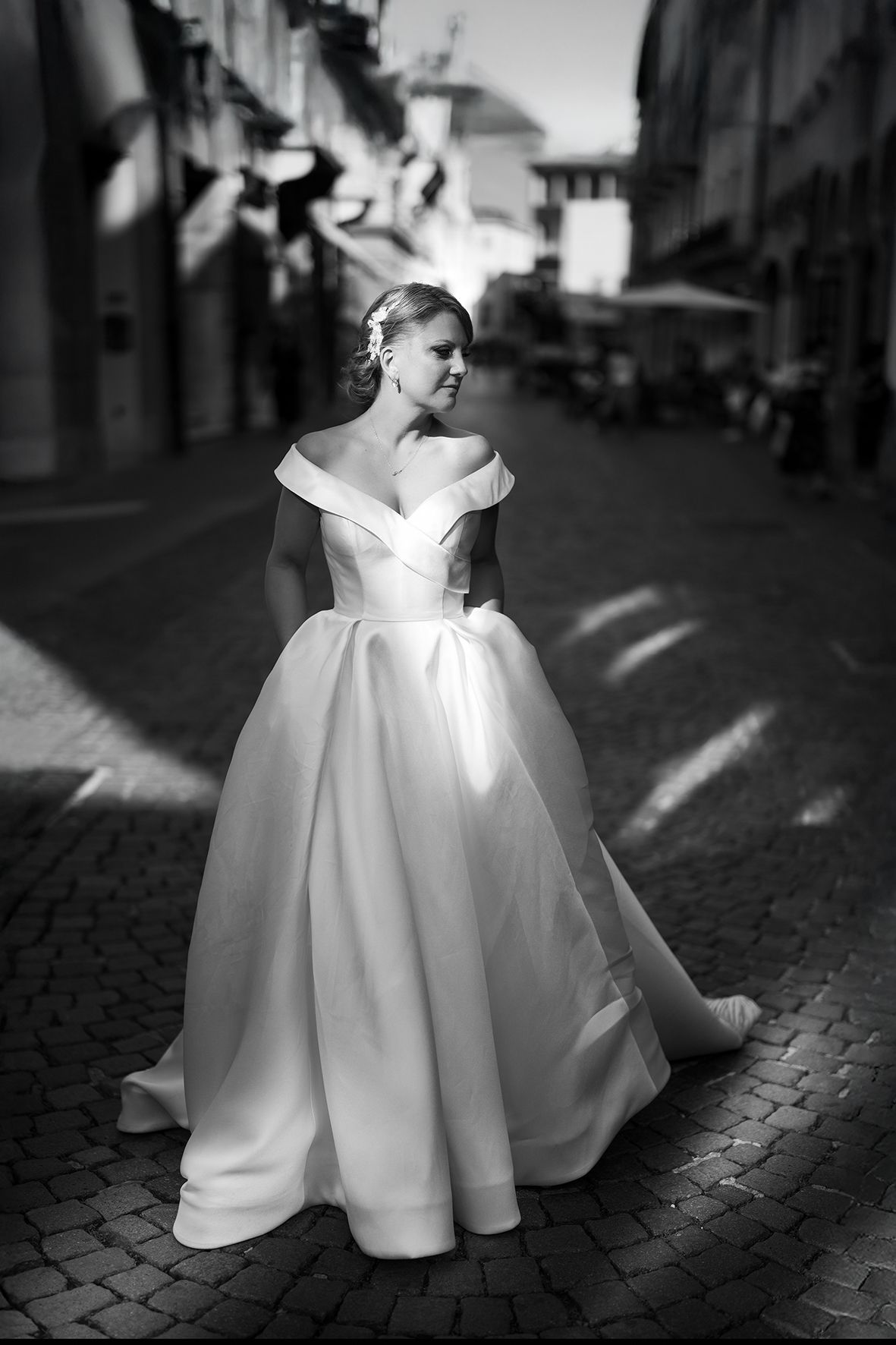 Dramatic black and white photos of a flowing white wedding dress on cobblestone streets.