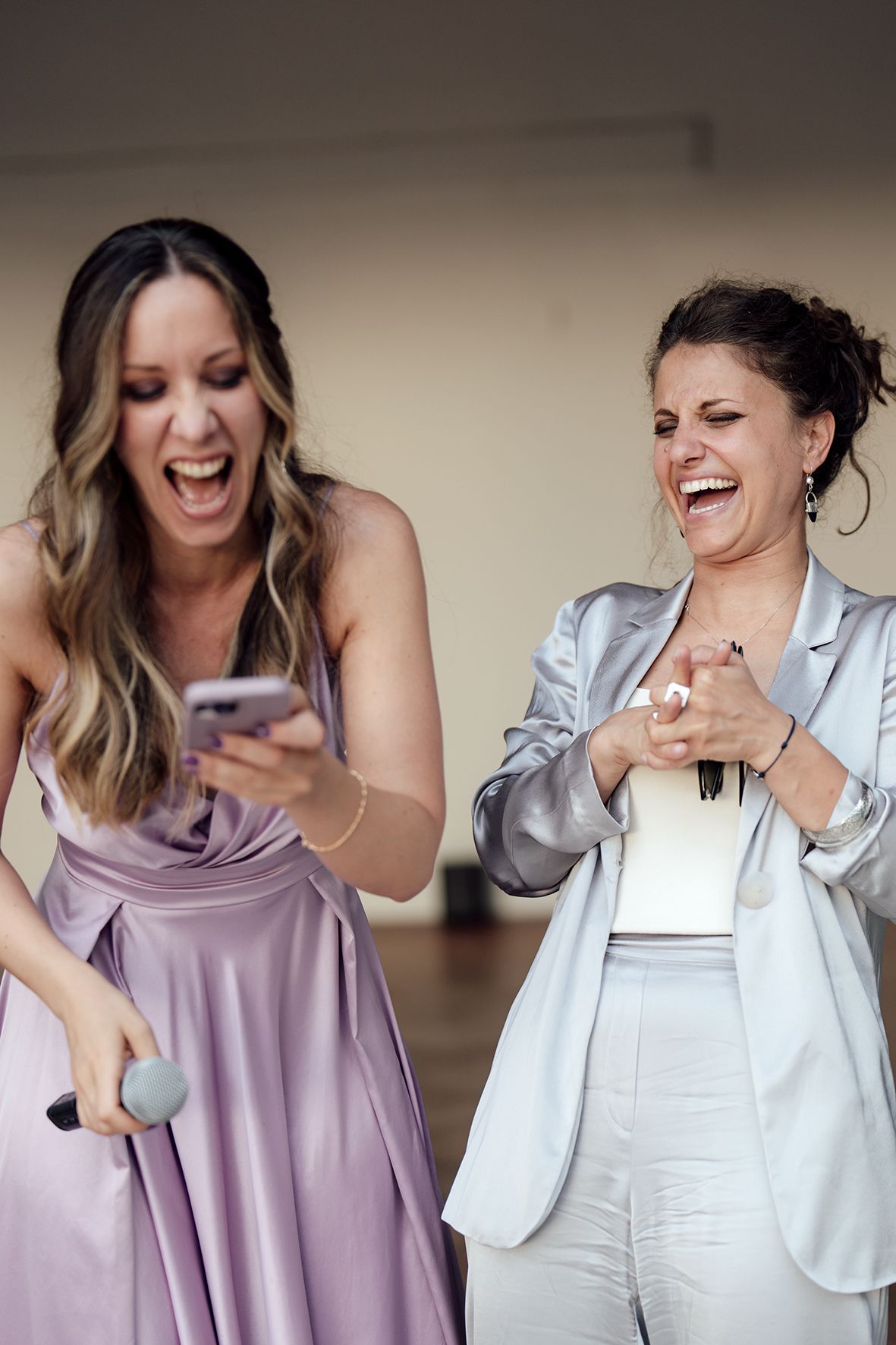 Wedding party members laugh and dance in purple dresses and white blazers.
