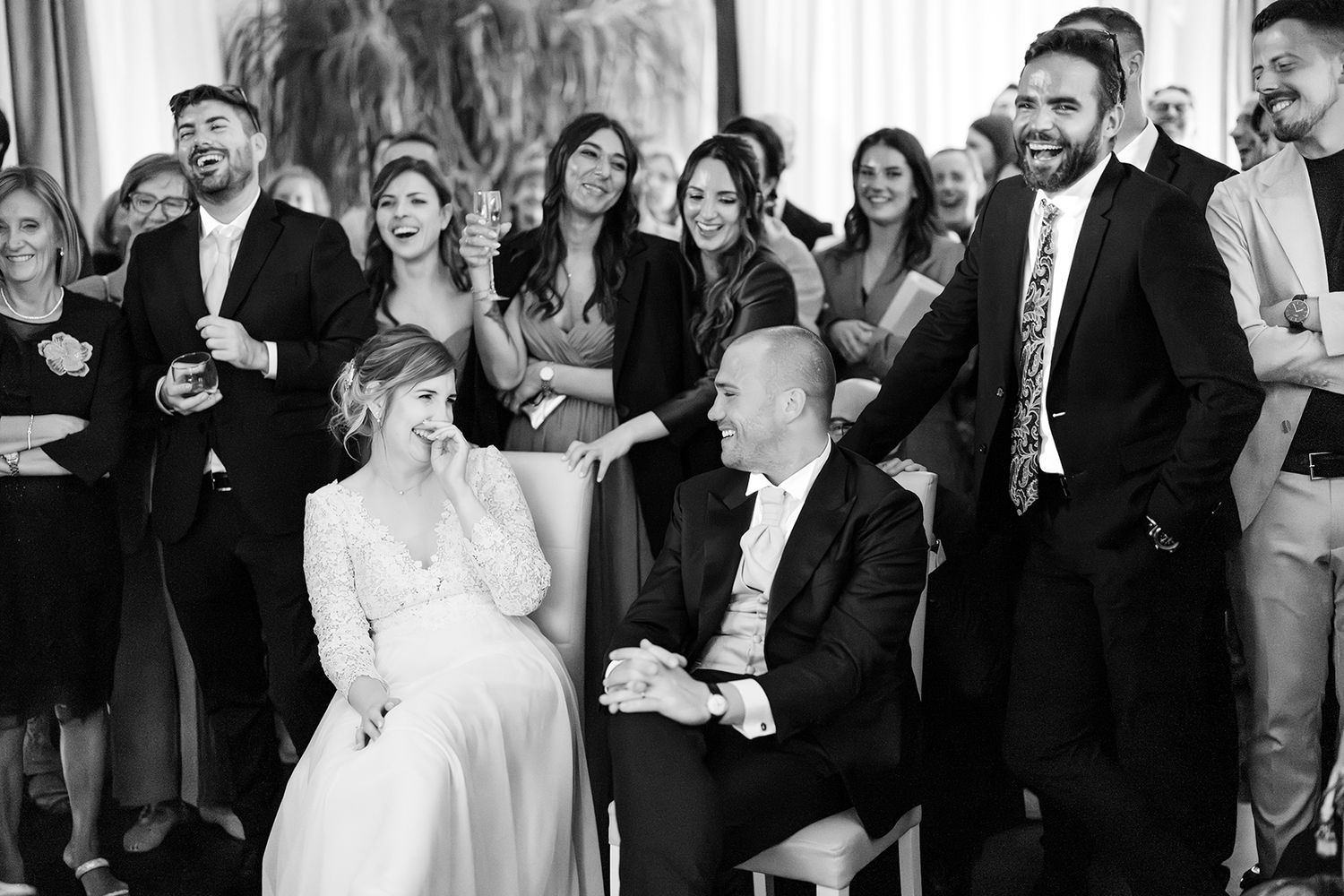 Large group of wedding attendees celebrating together in a bright indoor space.