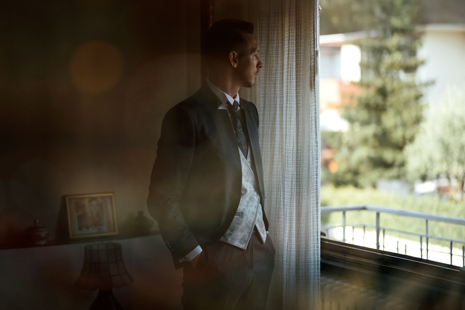 Moody wedding portraits taken through window light with soft focus effects.