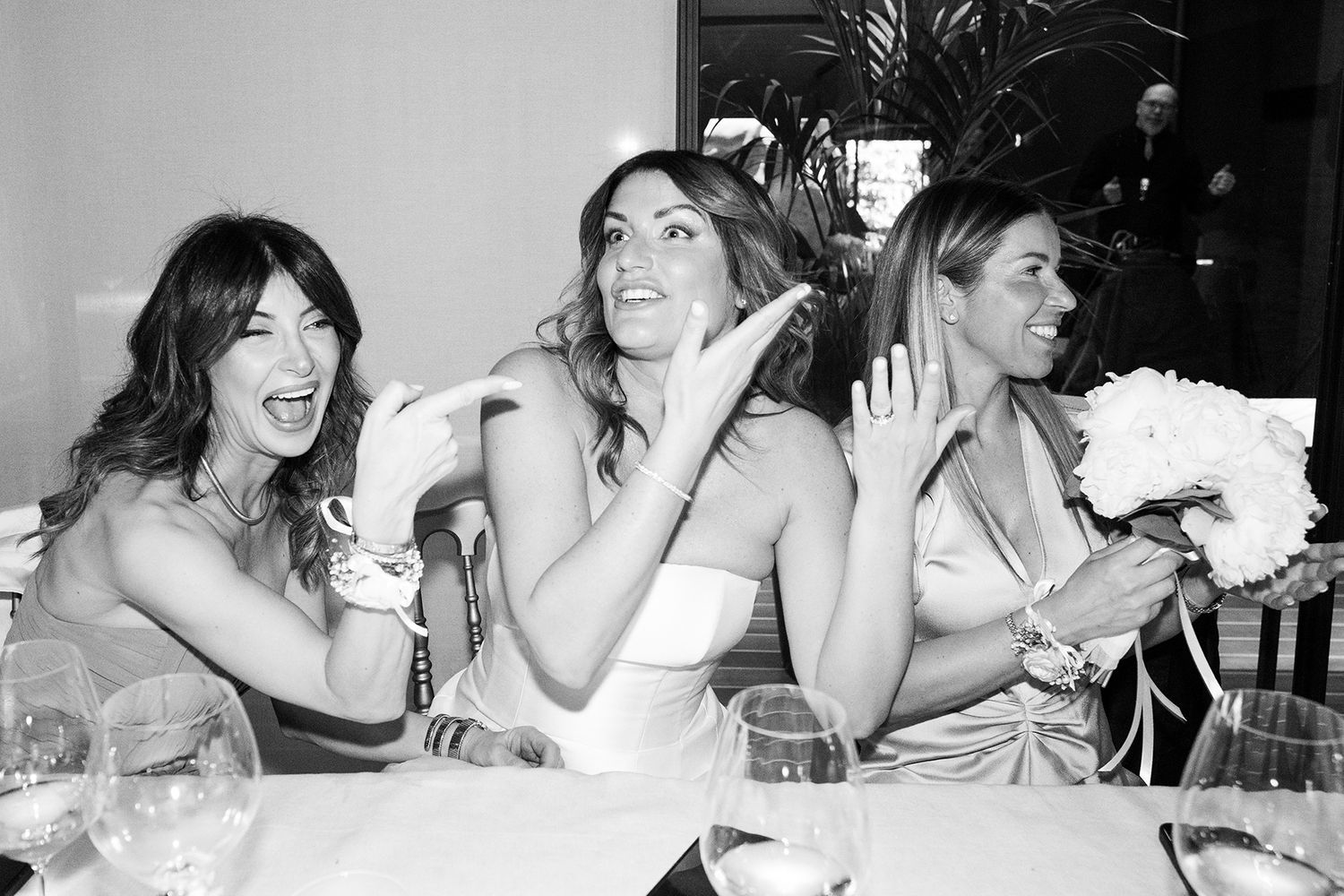 Black and white photos capture candid laughter among wedding guests at reception.