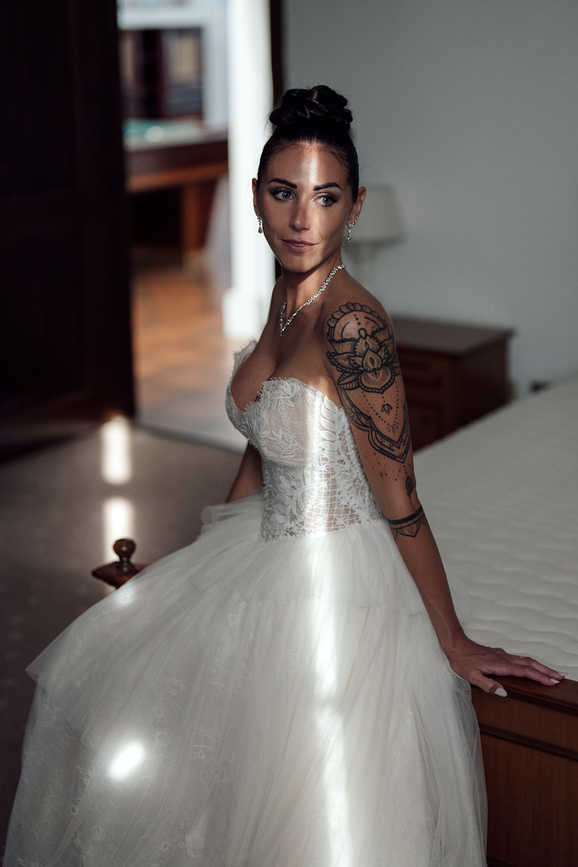 Bride in flowing white ballgown dress shows intricate details and tattoo artwork.