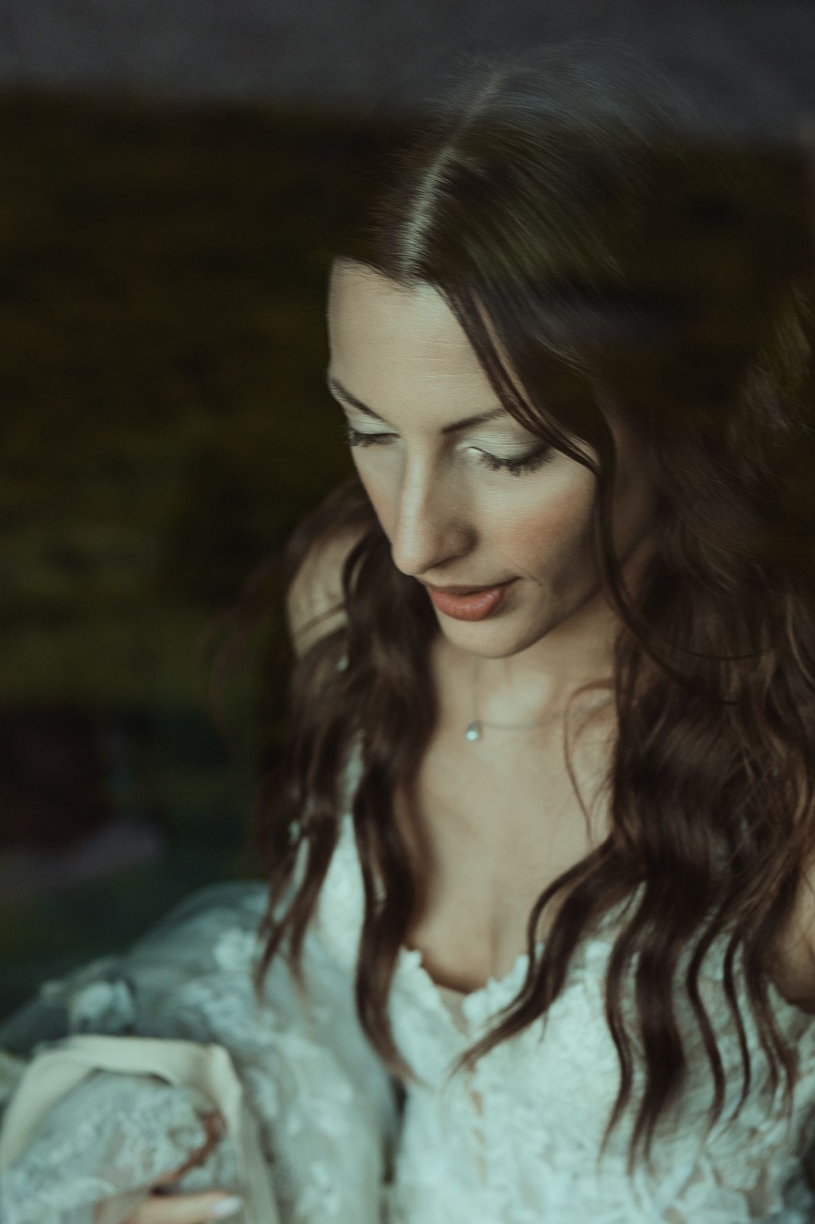 Ethereal bridal portrait with soft lighting highlighting lace dress details.