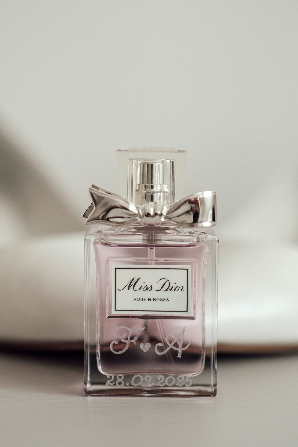 Miss Dior perfume bottle photographed in soft focus with delicate pink tones.