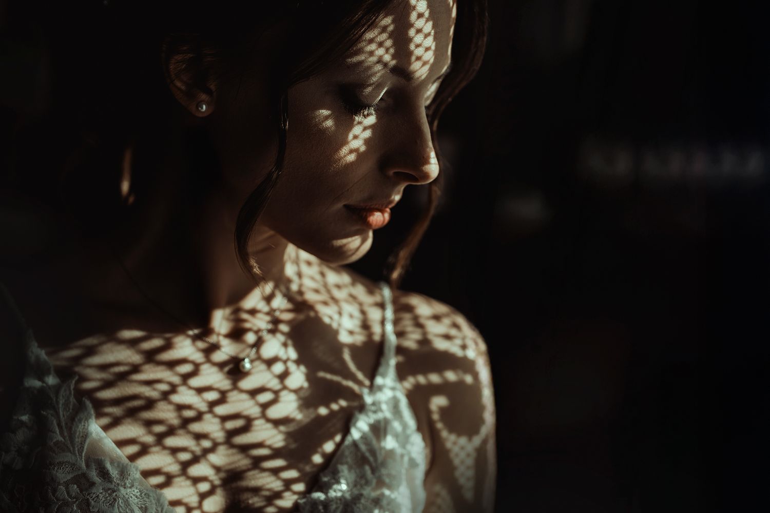 Lace curtains create delicate shadows and patterns in moody lighting.