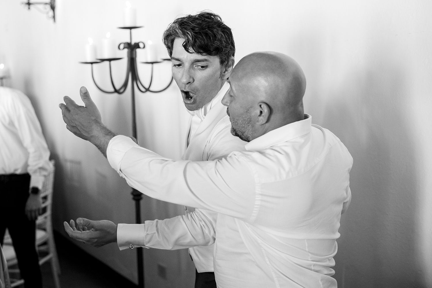 Black and white photo of guests celebrating with arms raised at a wedding reception.