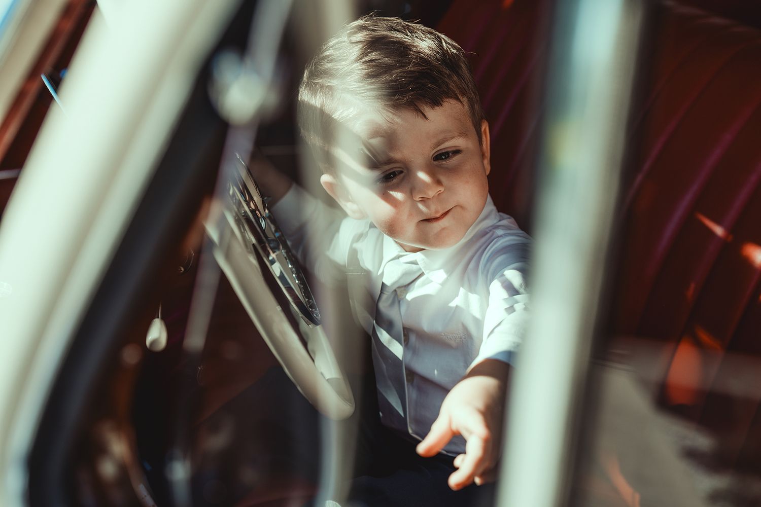 A vintage car interior view through the window showing red leather seats.