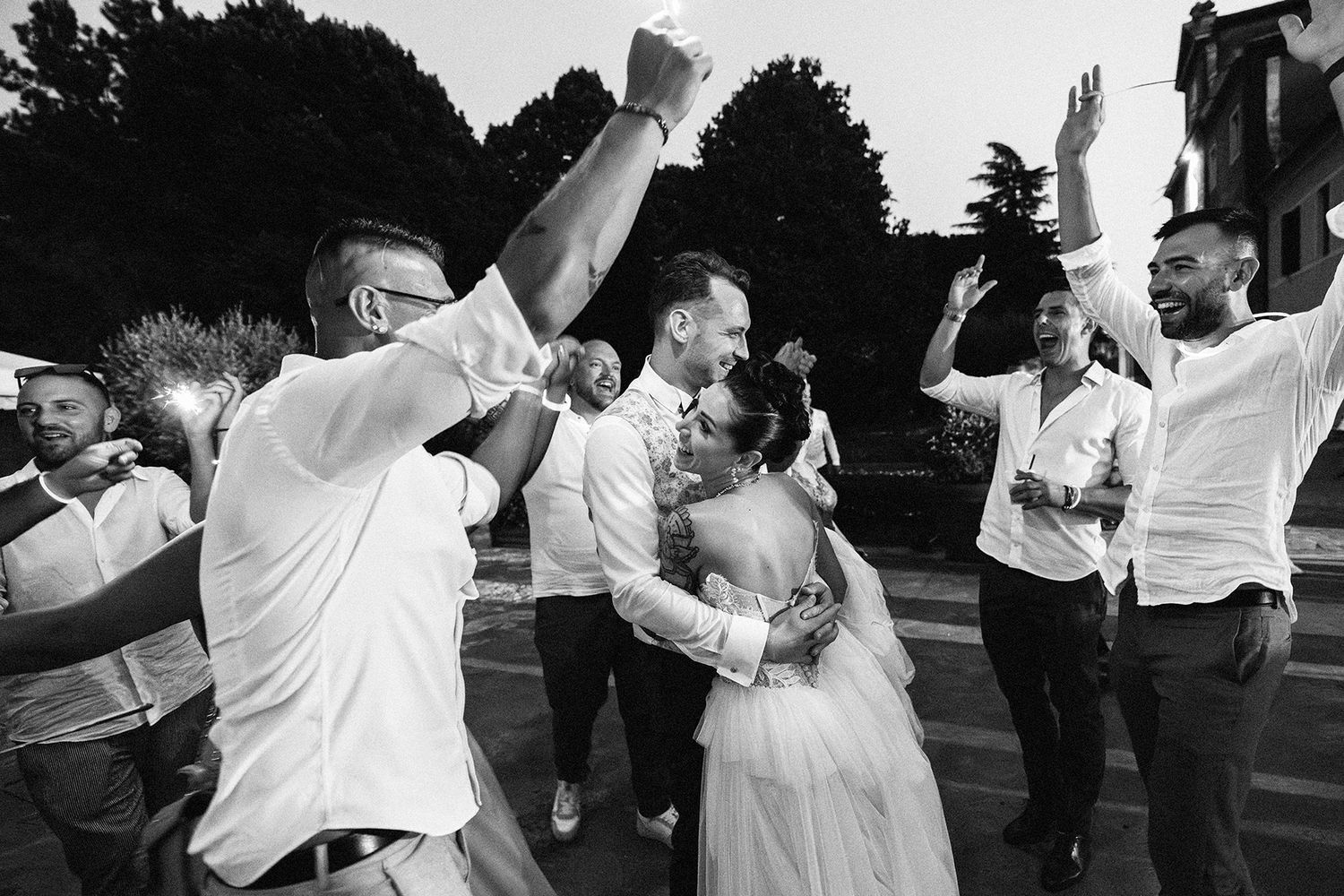 Black and white photo of wedding guests dancing energetically at a reception.