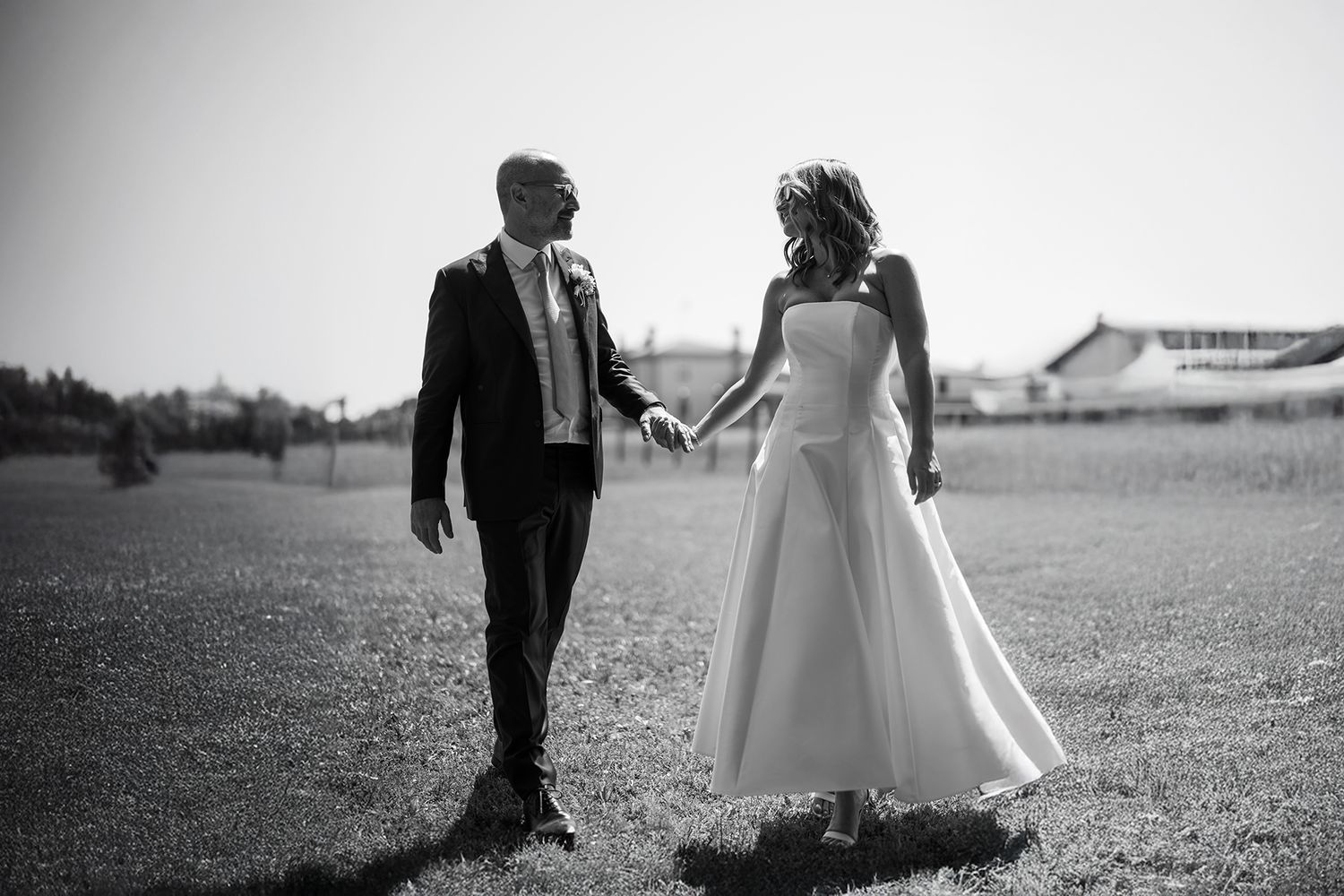 Black and white silhouettes of couple walking across an open field.