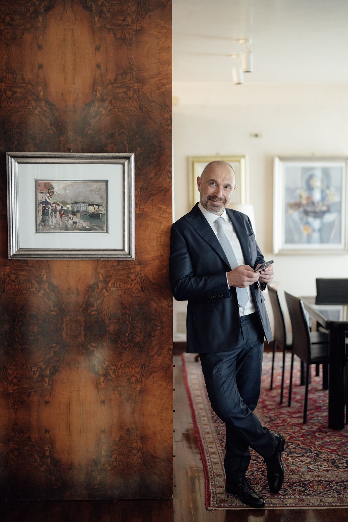 Professional portrait session in an elegant room with rustic walls and framed artwork.