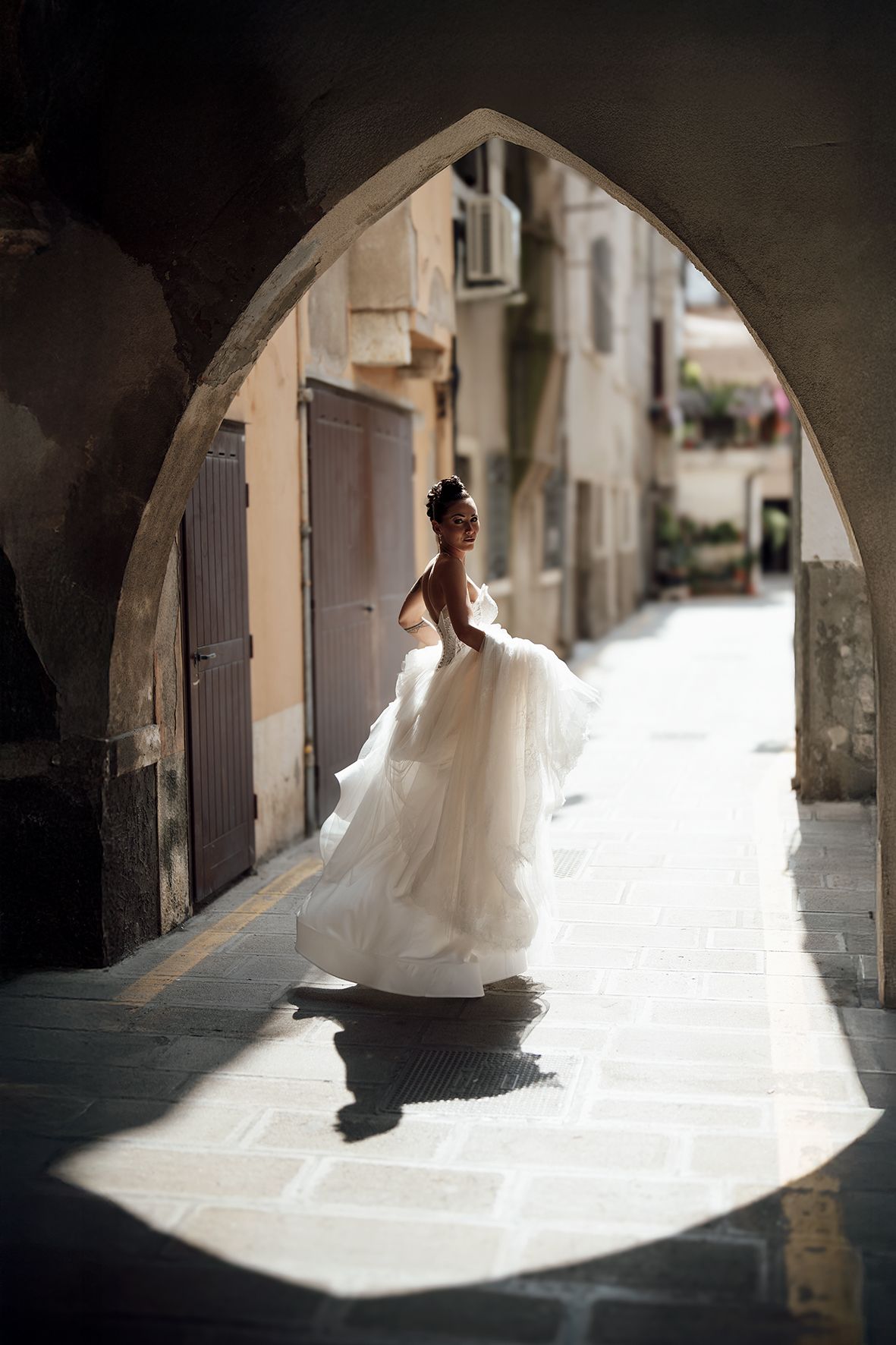 Artistic silhouette shots of a bride in flowing gown under stone archways.