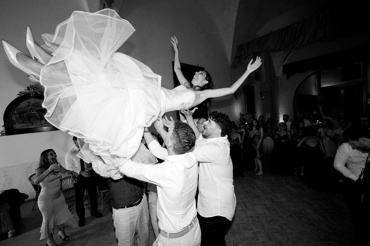 Wedding guests dancing with flowing dresses captured in dramatic black and white.