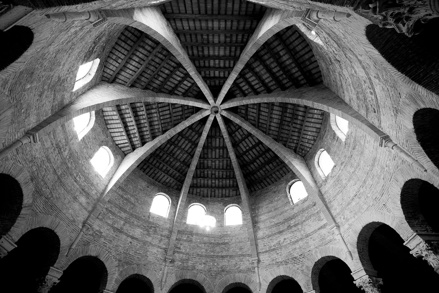 Black and white architectural photo of ornate domed church ceiling with radial pattern.