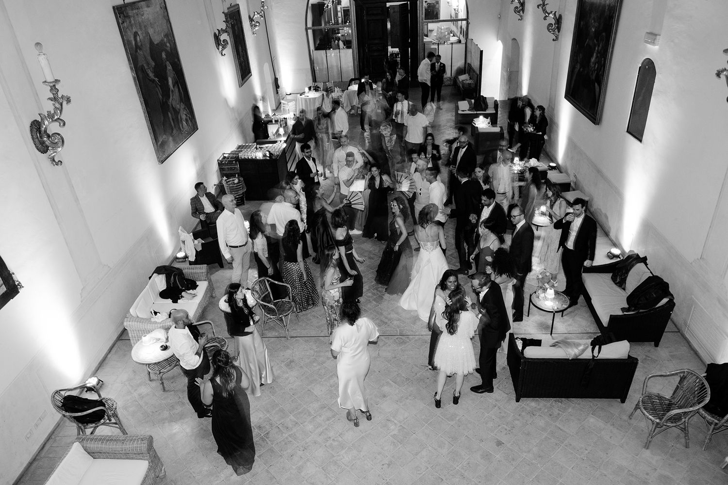 Wide angle view of an elegant white wedding reception hall filled with guests.