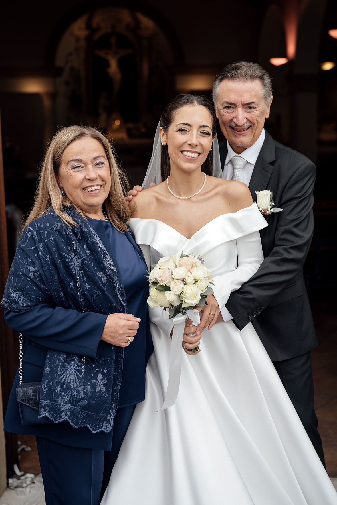 A wedding portrait featuring the bride in a classic white gown with guests in formal attire.