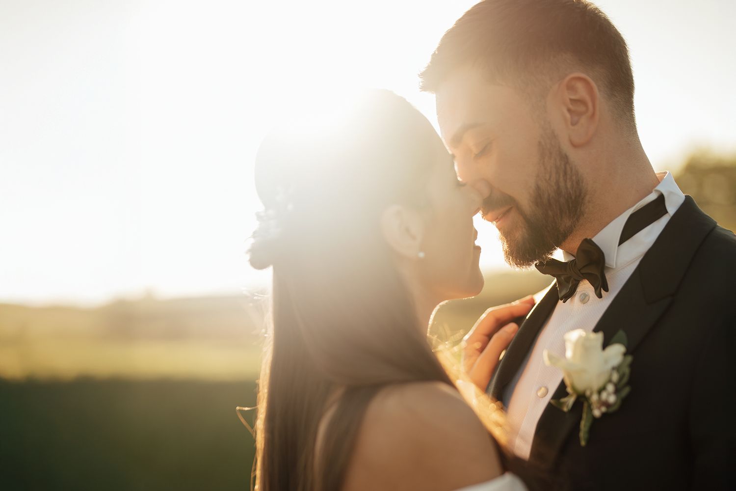 Golden sunset light illuminates a romantic wedding scene with soft bokeh effects.