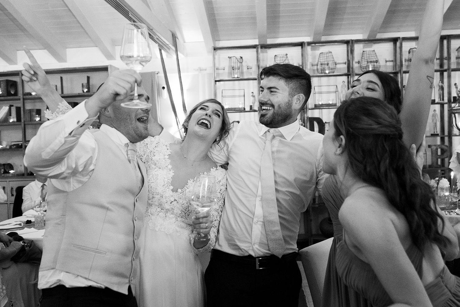 Wedding party celebrating with drinks and laughter at an indoor reception.