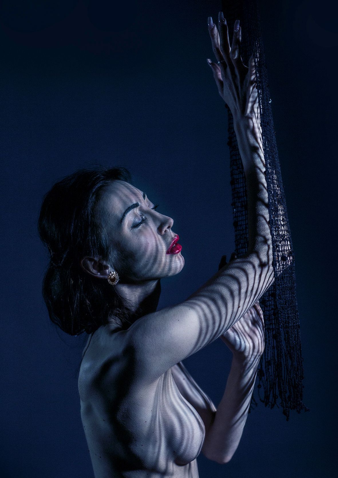 Dramatic blue-tinted studio portrait showing expressive movement and texture.