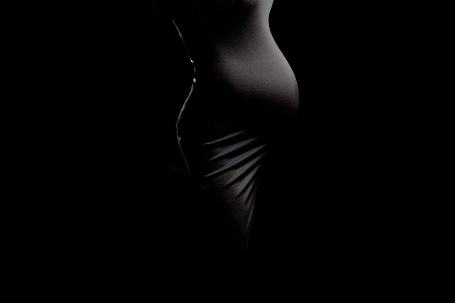 Artistic black and white photograph showing curves and shadows of a torso silhouette.