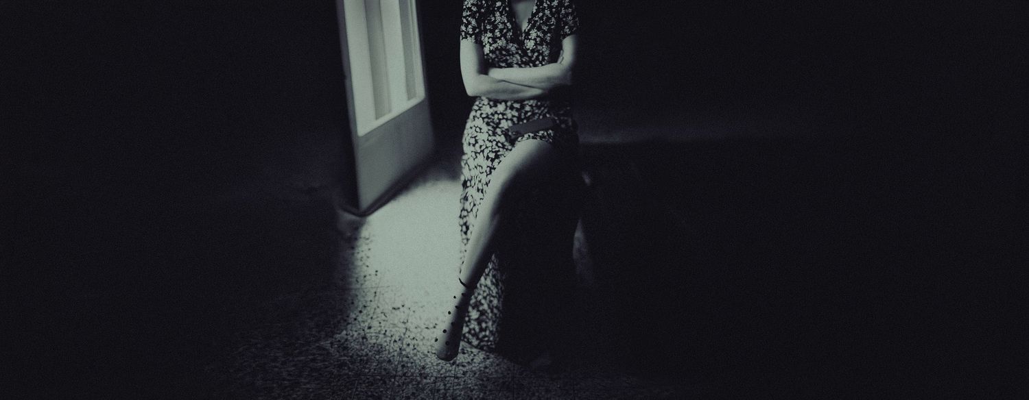 A black and white abstract photograph showing a blurred silhouette figure in motion against a dark background.