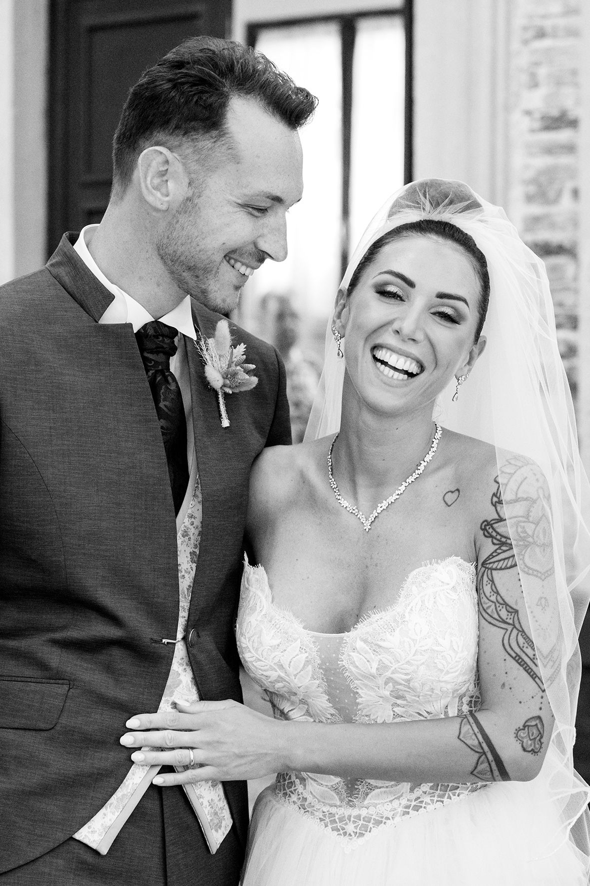 Black and white portrait of newlyweds sharing joyful laughter.