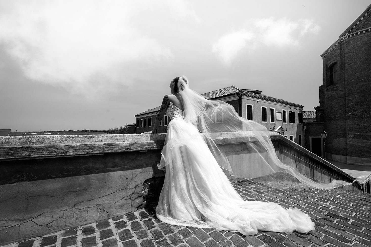 Dramatic black and white photos of flowing wedding dress against coastal backdrop.