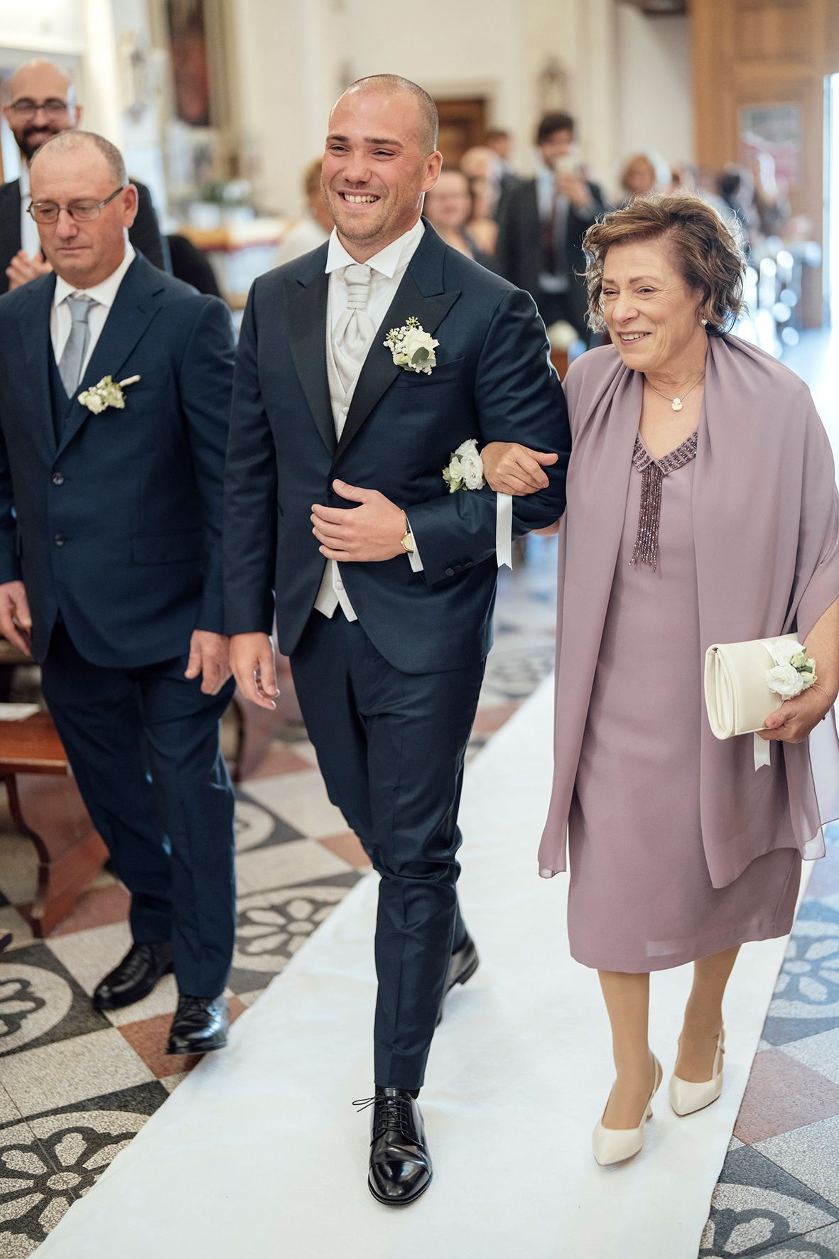 Wedding party members walking together on decorative floor in formal attire.