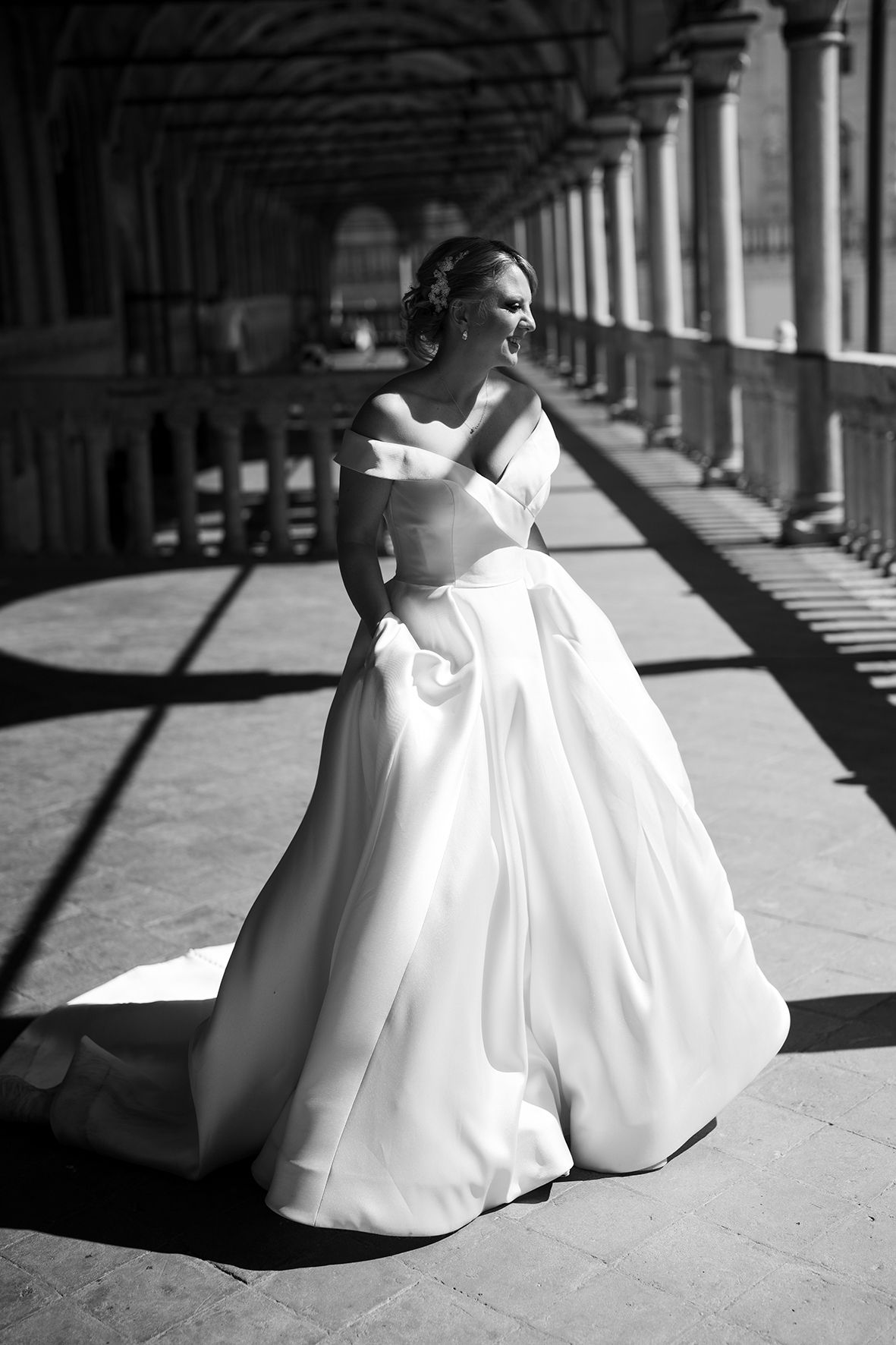 Dramatic black and white photos of a bride in a flowing white gown under arched columns.