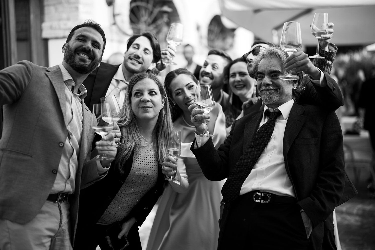 Black and white photo of wedding guests toasting with champagne glasses.