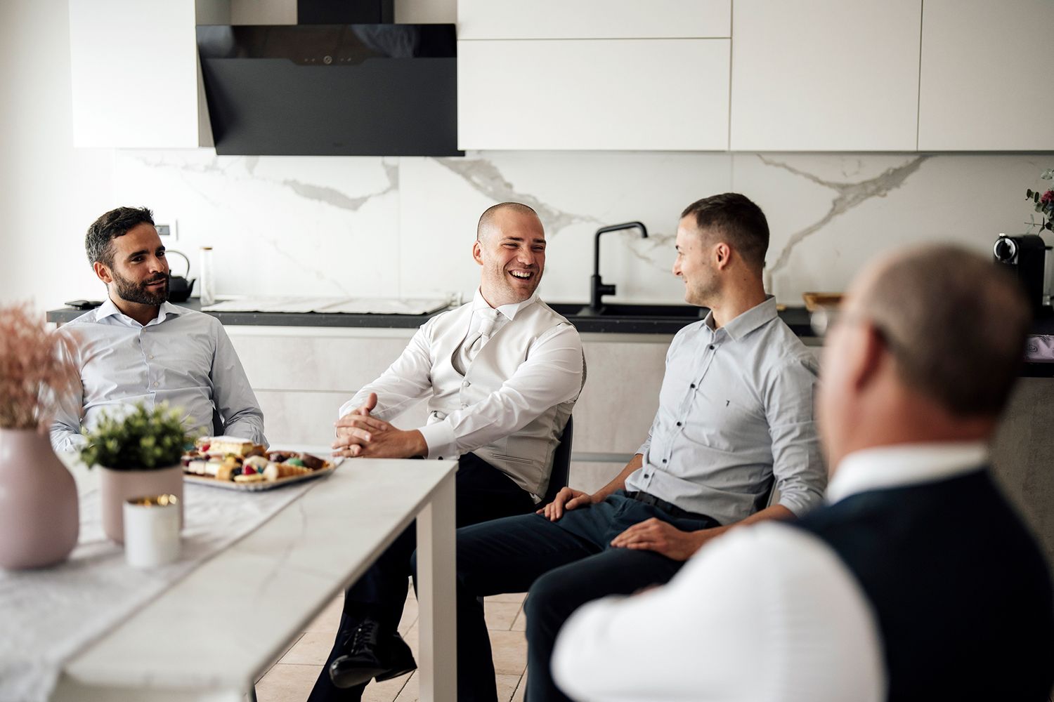 Friends gather in modern kitchen for casual conversation and laughter.